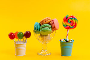 front-view-french-macarons-along-with-candies-lollipops-inside-buckets-yellow-sugar-sweet-confectionery-candy-300x200.jpg